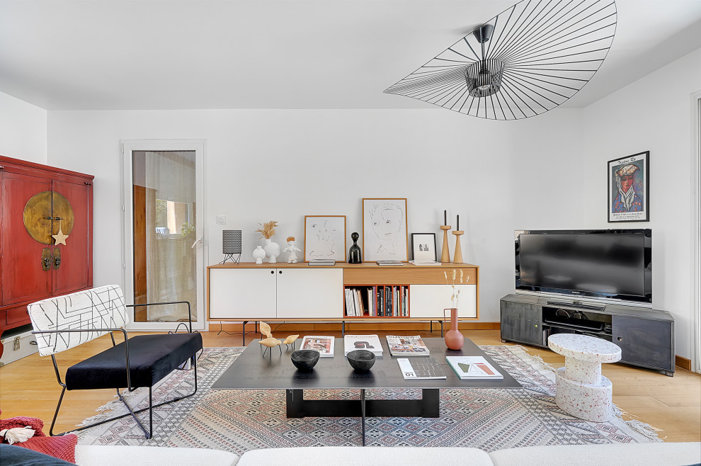 На фото: гостиная комната в современном стиле с белыми стенами, светлым паркетным полом, телевизором в углу и бежевым полом с