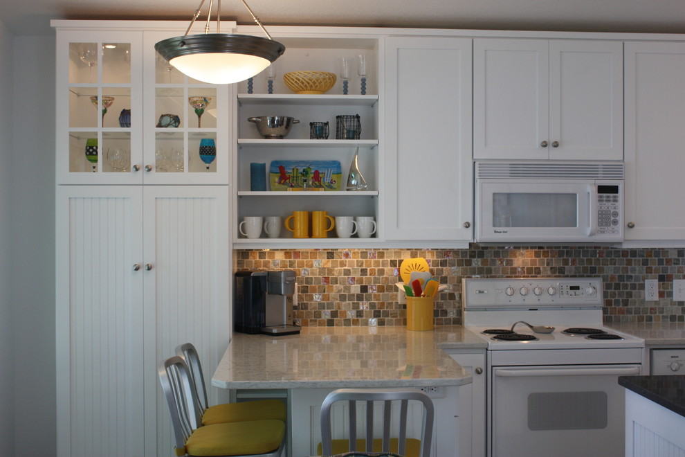 Home design - mid-sized transitional l-shaped home design idea with an undermount sink, recessed-panel cabinets, white cabinets, granite countertops, multicolored backsplash, mosaic tile backsplash, white appliances and a peninsula