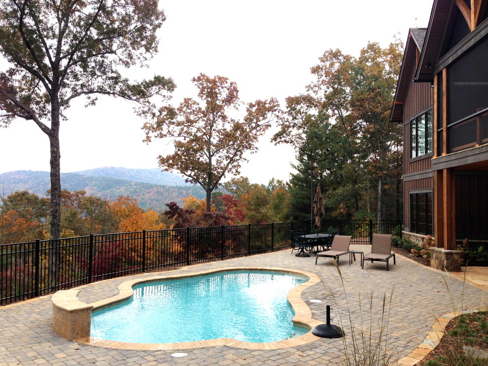 Large mountain style backyard concrete paver and custom-shaped natural pool photo