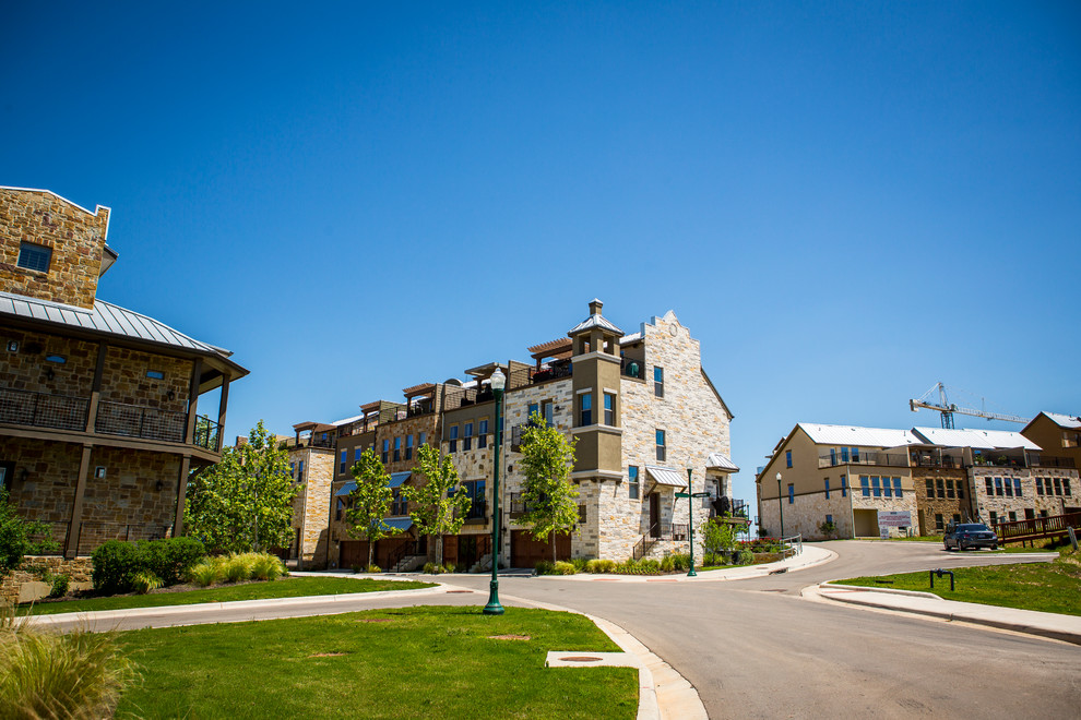 Huge transitional beige three-story stone exterior home idea in Austin with a hip roof