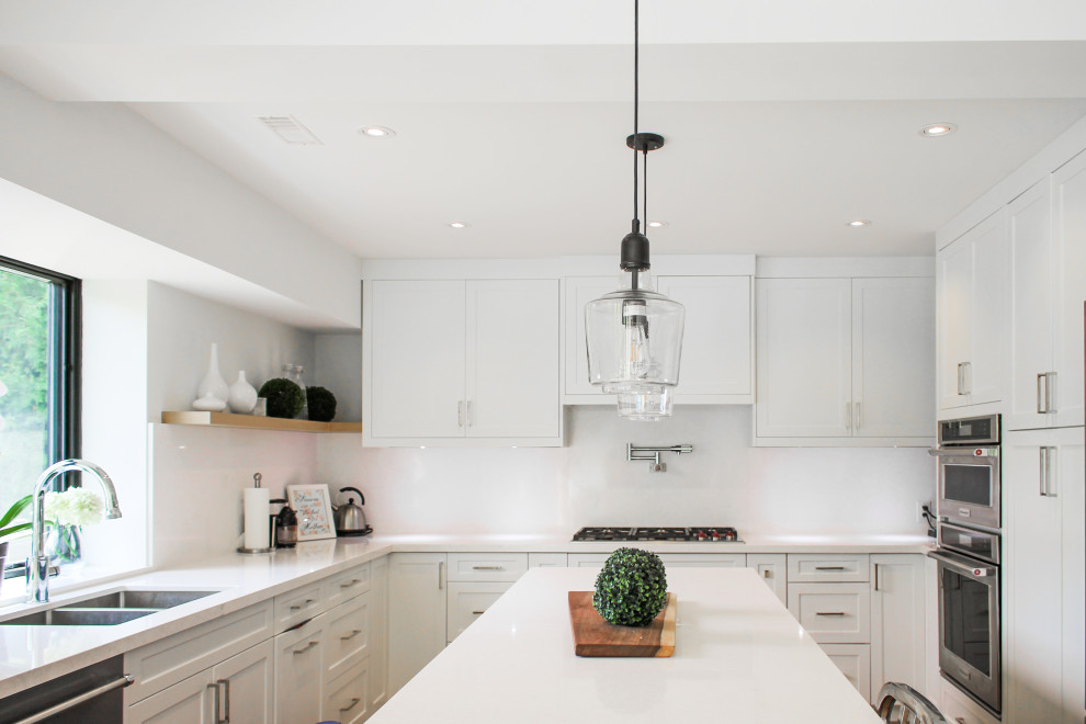 Inspiration for a large contemporary u-shaped eat-in kitchen in Toronto with an integrated sink, shaker cabinets, white cabinets, marble benchtops, white splashback, marble splashback, stainless steel appliances, light hardwood floors, with island, beige floor and white benchtop.