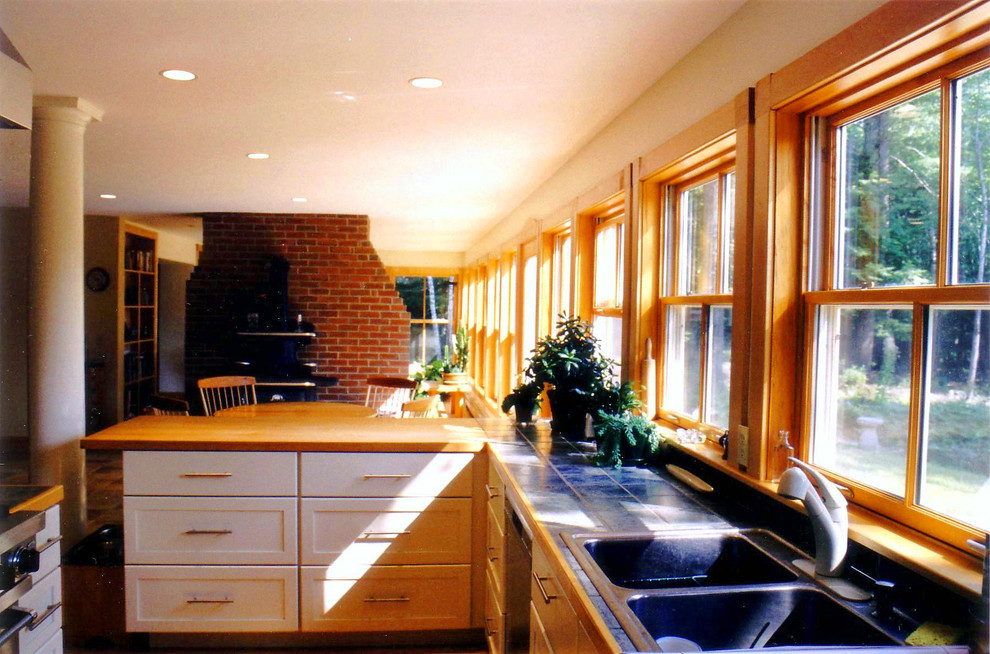 Design ideas for a mid-sized arts and crafts u-shaped open plan kitchen in Portland Maine with a drop-in sink, recessed-panel cabinets, white cabinets, tile benchtops, blue splashback, ceramic splashback, stainless steel appliances and marble floors.