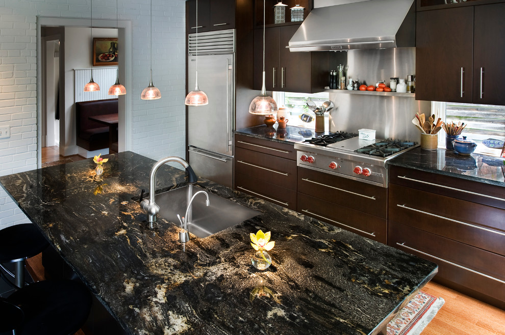 Mid-sized transitional galley light wood floor open concept kitchen photo in DC Metro with an undermount sink, flat-panel cabinets, dark wood cabinets, granite countertops, metallic backsplash, stainless steel appliances and an island