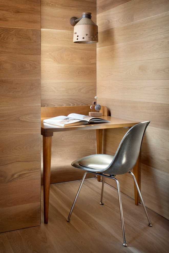 This is an example of a modern home office in San Francisco with light hardwood floors and a freestanding desk.