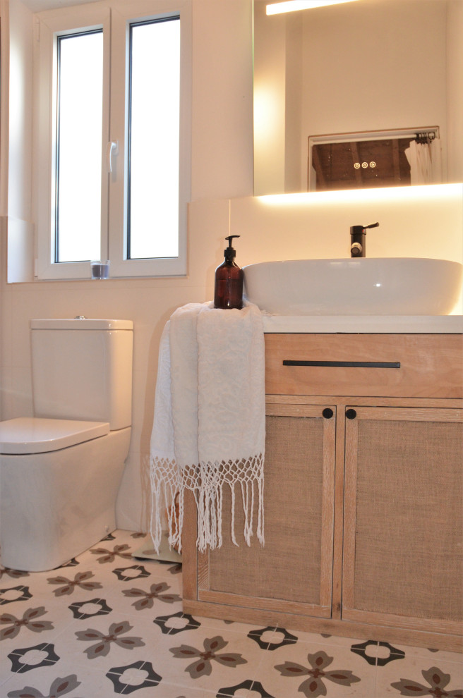 Bild på ett mellanstort minimalistiskt vit vitt badrum med dusch, med luckor med glaspanel, vita skåp, en kantlös dusch, svart och vit kakel, keramikplattor, vita väggar, klinkergolv i porslin, ett fristående handfat, flerfärgat golv och dusch med skjutdörr