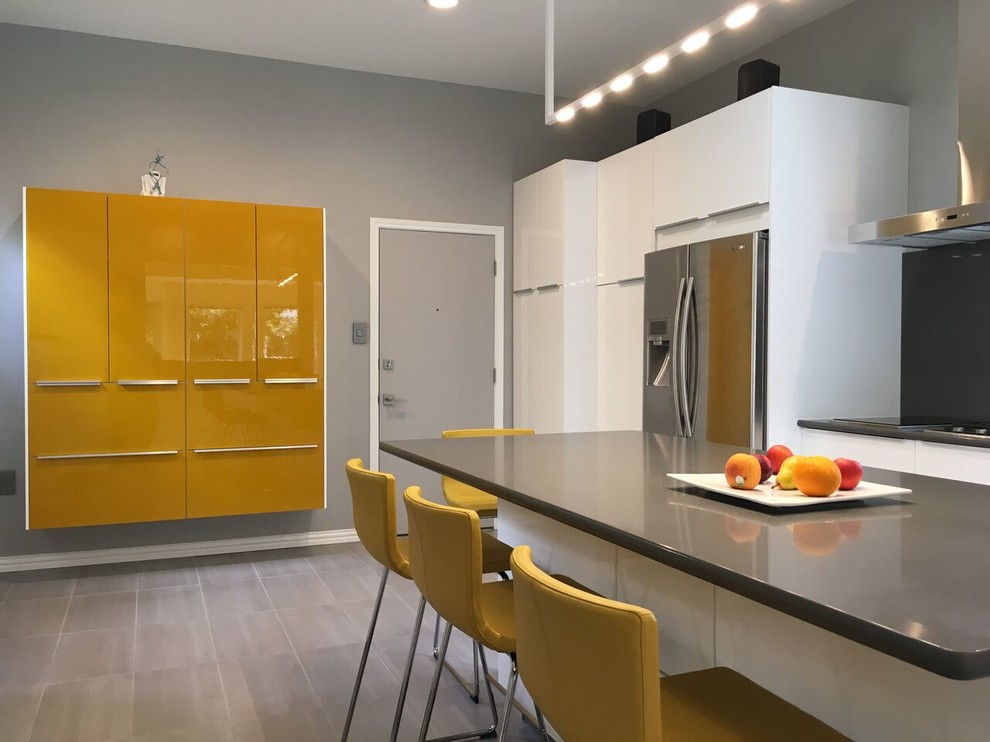 This is an example of a medium sized modern u-shaped kitchen/diner in Austin with a submerged sink, flat-panel cabinets, white cabinets, black splashback, stone slab splashback, stainless steel appliances, an island and grey floors.