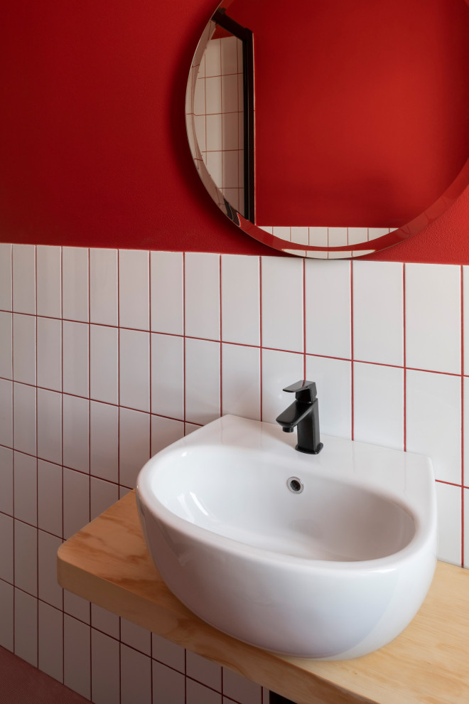 Photo of a medium sized contemporary cloakroom in Venice with open cabinets, light wood cabinets, a two-piece toilet, white tiles, ceramic tiles, red walls, porcelain flooring, a wall-mounted sink, wooden worktops, pink floors and a floating vanity unit.