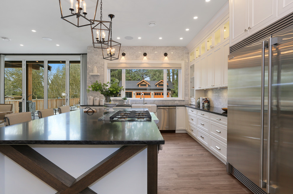 This is an example of a large contemporary l-shaped eat-in kitchen in Vancouver with a farmhouse sink, shaker cabinets, turquoise cabinets, soapstone benchtops, grey splashback, stone tile splashback, stainless steel appliances, medium hardwood floors, with island and brown floor.