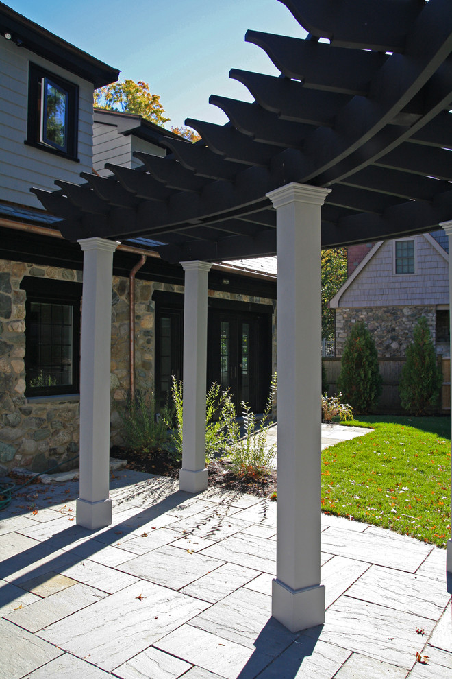 This is an example of a mid-sized traditional backyard patio in Boston with concrete pavers and a pergola.
