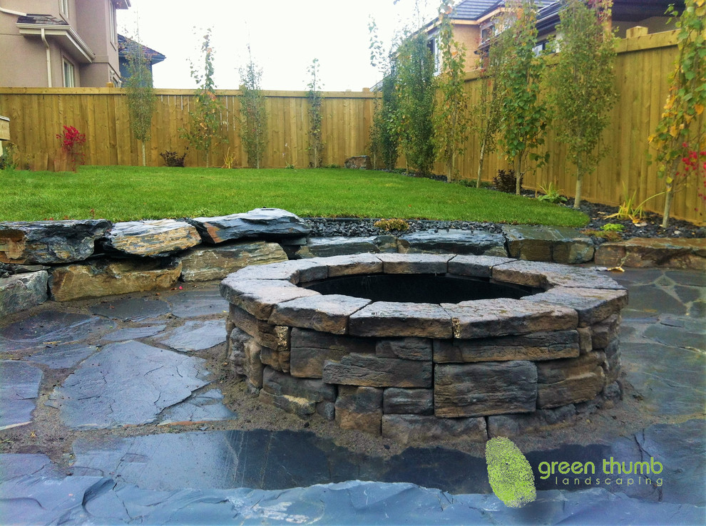Inspiration for a rustic full sun backyard stone landscaping in Edmonton with a fire pit for summer.
