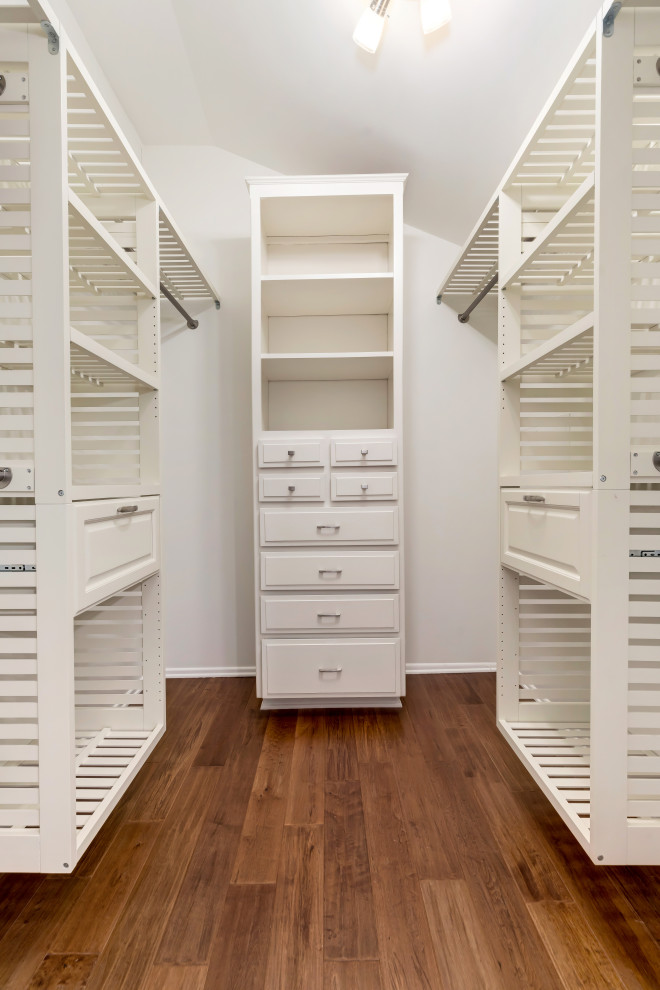 Ejemplo de armario vestidor unisex costero de tamaño medio con armarios con puertas mallorquinas, puertas de armario blancas y suelo de madera oscura