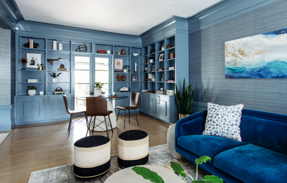 Design ideas for a large transitional open concept family room in San Francisco with a library, blue walls, light hardwood floors, a built-in media wall and beige floor.