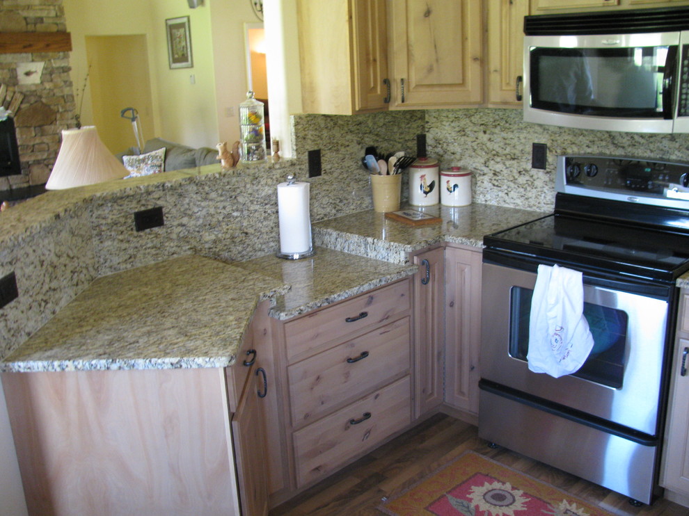 Medium tone wood floor eat-in kitchen photo with granite countertops, stone slab backsplash and stainless steel appliances