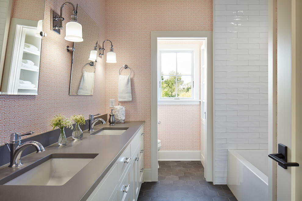 This is an example of a mid-sized country bathroom in Minneapolis with white cabinets, a two-piece toilet, white tile, multi-coloured walls, beaded inset cabinets, an alcove tub, ceramic tile, ceramic floors, an undermount sink, engineered quartz benchtops, grey benchtops and an enclosed toilet.