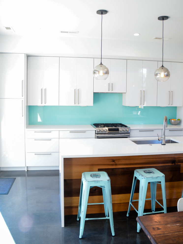 Design ideas for a mid-sized modern single-wall eat-in kitchen in Charlotte with an undermount sink, flat-panel cabinets, white cabinets, quartz benchtops, blue splashback, glass sheet splashback, stainless steel appliances, concrete floors and with island.