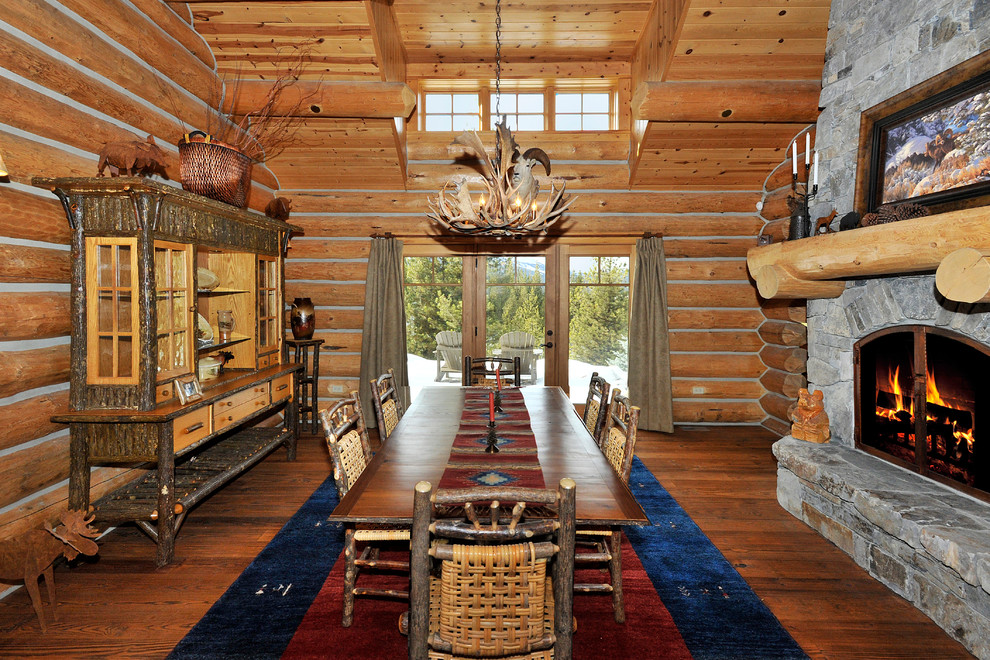 Mid-sized mountain style medium tone wood floor kitchen/dining room combo photo with a two-sided fireplace and a stone fireplace