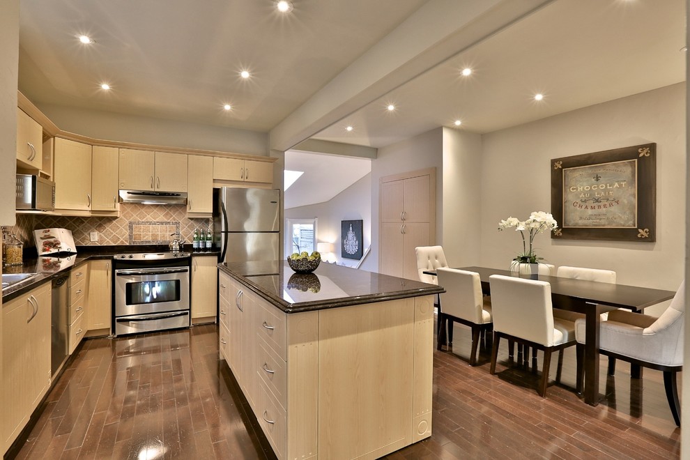Photo of a transitional l-shaped eat-in kitchen in Toronto with light wood cabinets, ceramic splashback, stainless steel appliances, medium hardwood floors and with island.