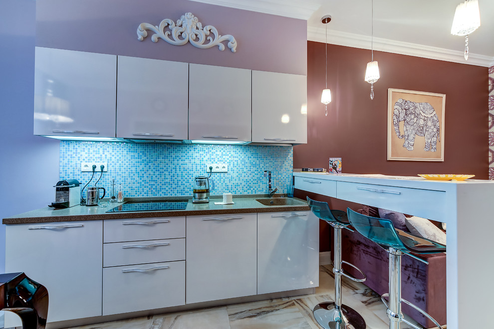 This is an example of a contemporary l-shaped open plan kitchen in Orlando with an integrated sink, flat-panel cabinets, white cabinets, mosaic tile splashback, porcelain floors and a peninsula.