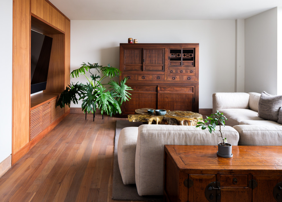 Foto di un soggiorno etnico chiuso con pareti bianche, pavimento in legno massello medio e parete attrezzata