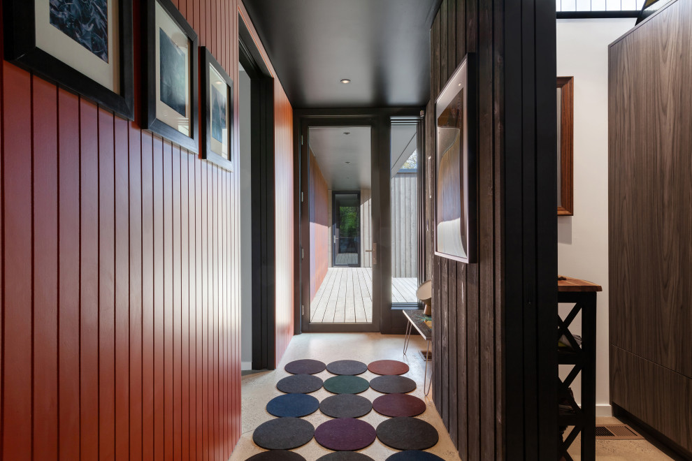 Inspiration for a small modern hallway in Indianapolis with brown walls, concrete flooring, a single front door, a black front door, grey floors, wood walls and a feature wall.
