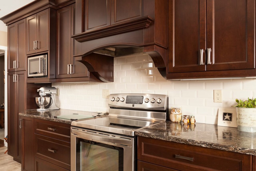 Inspiration for a transitional kitchen remodel in Toronto with shaker cabinets, dark wood cabinets, granite countertops, white backsplash, subway tile backsplash and stainless steel appliances