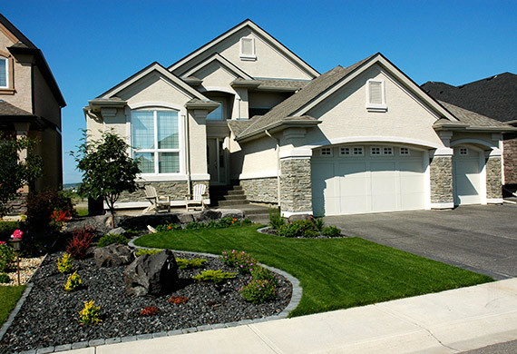 Photo of a mid-sized traditional front yard full sun driveway for spring in Calgary with natural stone pavers.