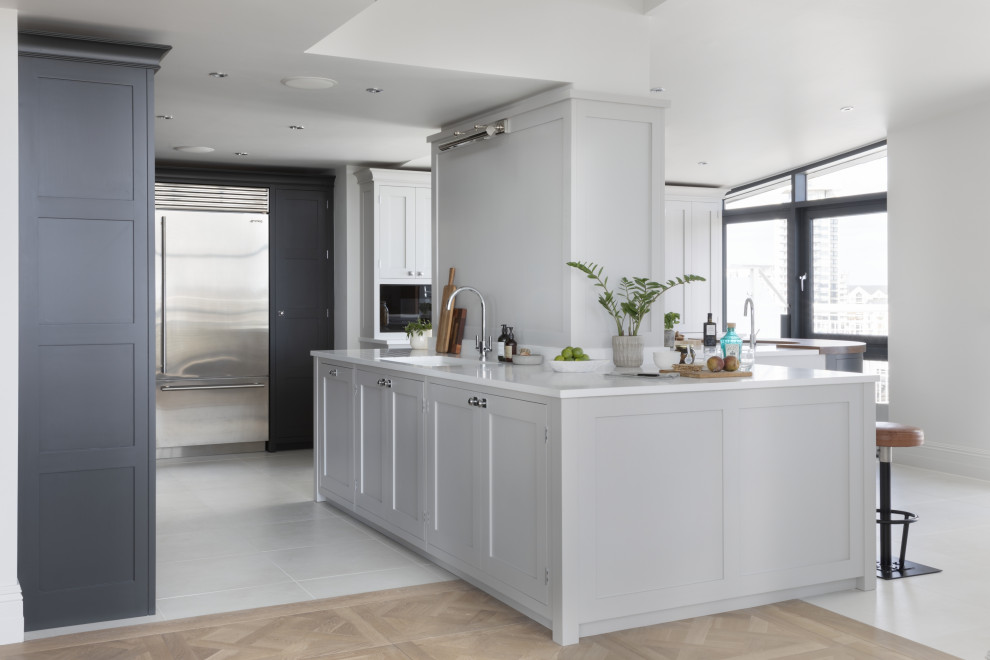 Large transitional l-shaped porcelain tile and gray floor eat-in kitchen photo in London with an undermount sink, shaker cabinets, gray cabinets, quartzite countertops, mirror backsplash, stainless steel appliances, an island and white countertops