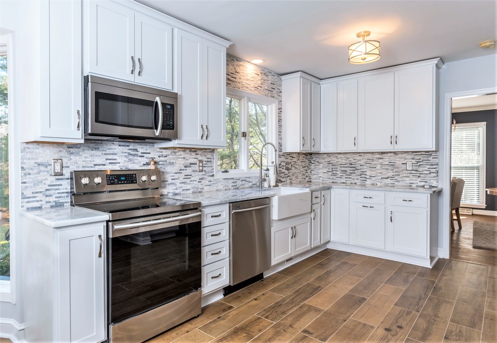 Eat-in kitchen - large transitional l-shaped ceramic tile and brown floor eat-in kitchen idea in Baltimore with a farmhouse sink, shaker cabinets, white cabinets, granite countertops, gray backsplash, stone tile backsplash, stainless steel appliances, no island and white countertops