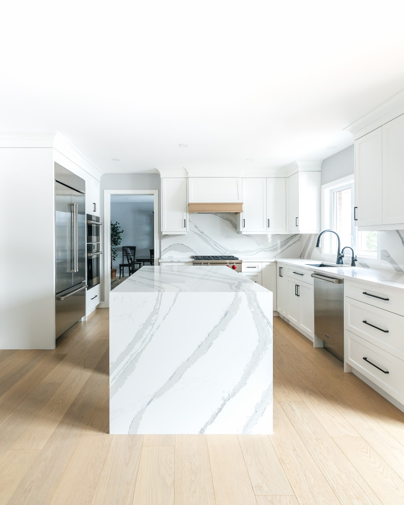 Eat-in kitchen - mid-sized transitional u-shaped light wood floor eat-in kitchen idea in Toronto with an undermount sink, shaker cabinets, white cabinets, quartz countertops, white backsplash, quartz backsplash, stainless steel appliances, an island and white countertops