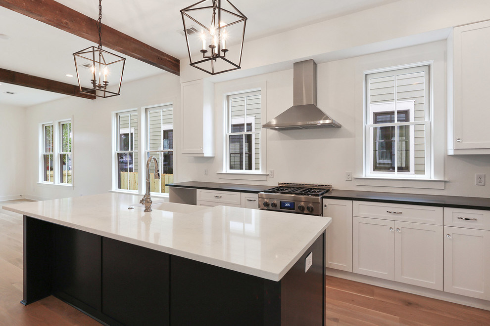 Design ideas for a mid-sized country l-shaped open plan kitchen in Charleston with a farmhouse sink, shaker cabinets, white cabinets, quartz benchtops, stainless steel appliances, light hardwood floors, with island and multi-coloured floor.
