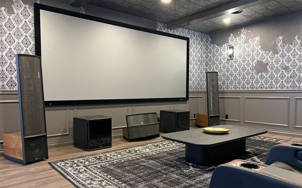 Idée de décoration pour une très grande salle de cinéma bohème ouverte avec un mur gris, un sol en bois brun, un écran de projection et un sol marron.