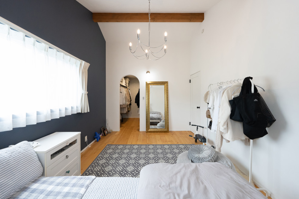 Diseño de dormitorio principal y blanco de estilo de casa de campo con paredes blancas, suelo de contrachapado, suelo marrón, vigas vistas y papel pintado