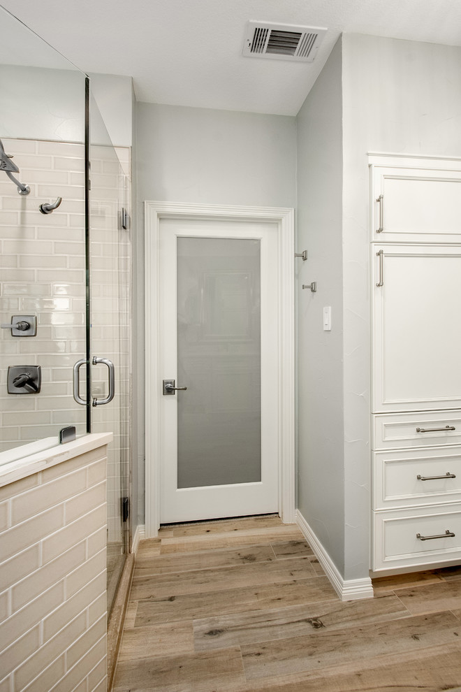 Mid-sized transitional master bathroom in Dallas with recessed-panel cabinets, white cabinets, a corner shower, a two-piece toilet, gray tile, marble, grey walls, porcelain floors, an undermount sink, engineered quartz benchtops, brown floor, a hinged shower door and white benchtops.