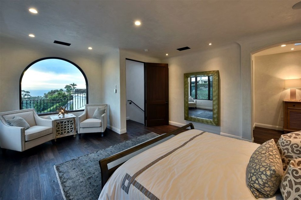 Large contemporary master bedroom in San Diego with white walls and brown floor.