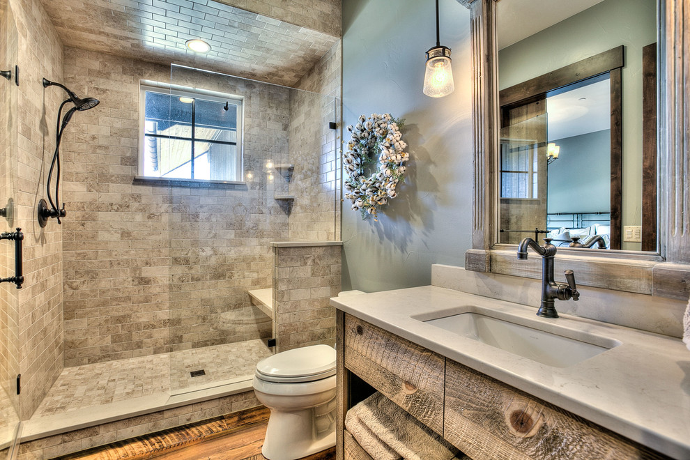 This is an example of a mid-sized country 3/4 bathroom in Denver with flat-panel cabinets, medium wood cabinets, an alcove shower, a two-piece toilet, beige tile, multi-coloured tile, ceramic tile, green walls, medium hardwood floors, an undermount sink and engineered quartz benchtops.