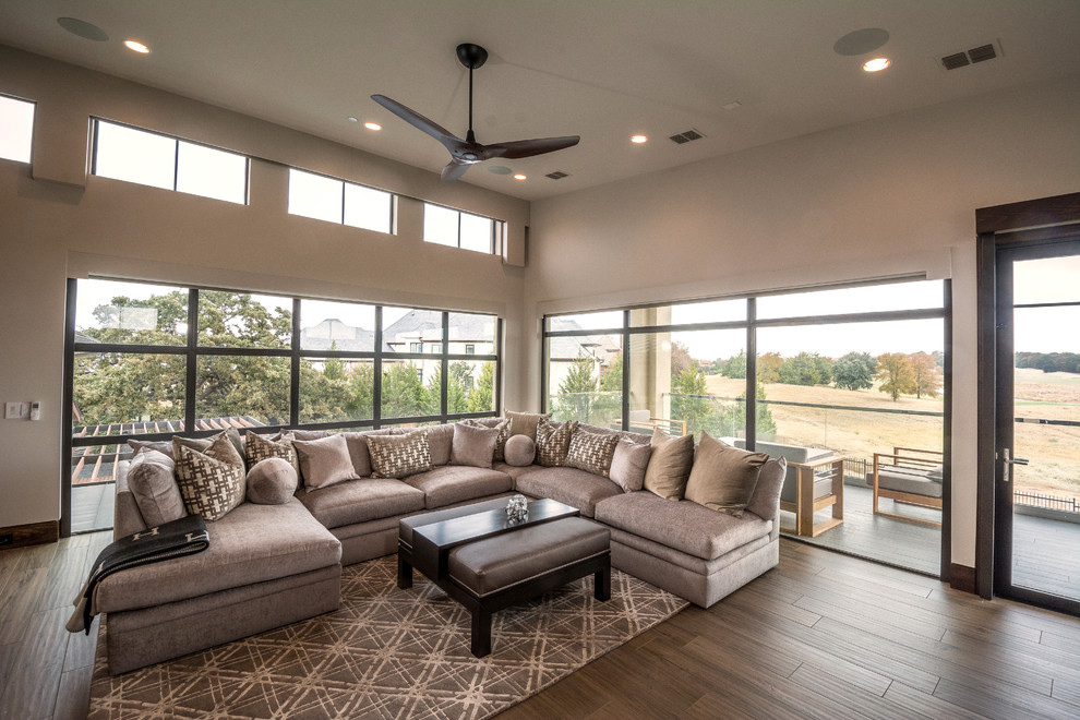 Design ideas for an expansive contemporary open concept family room in Orange County with a game room, beige walls, porcelain floors, a wall-mounted tv and brown floor.
