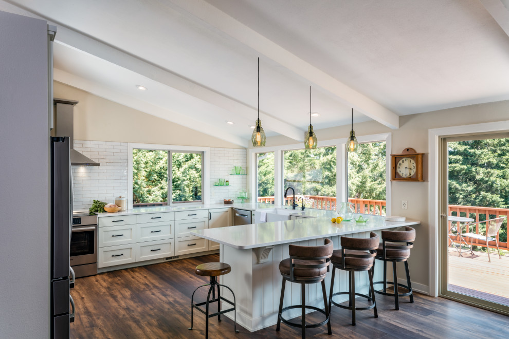 Large country u-shaped dark wood floor and brown floor open concept kitchen photo in Other with an undermount sink, shaker cabinets, white cabinets, quartz countertops, white backsplash, porcelain backsplash, stainless steel appliances, a peninsula and white countertops