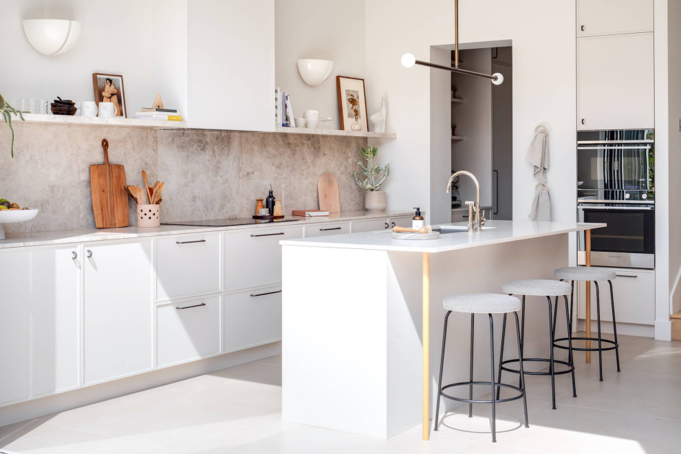 Photo of a large contemporary single-wall open plan kitchen in London with beaded cabinets, beige cabinets, marble worktops and an island.