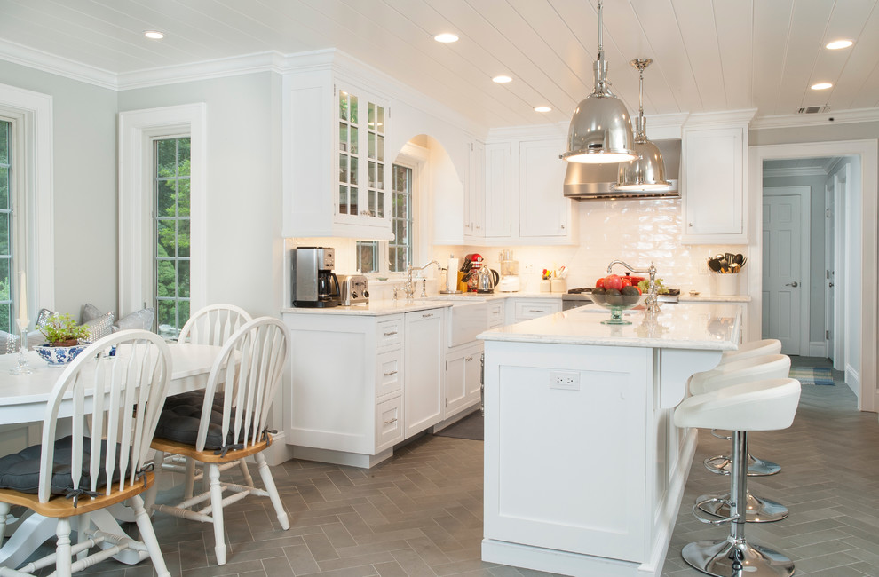 Inspiration for a mid-sized traditional l-shaped eat-in kitchen in New York with a farmhouse sink, shaker cabinets, white cabinets, white splashback, subway tile splashback, with island, marble benchtops, stainless steel appliances, slate floors and grey floor.