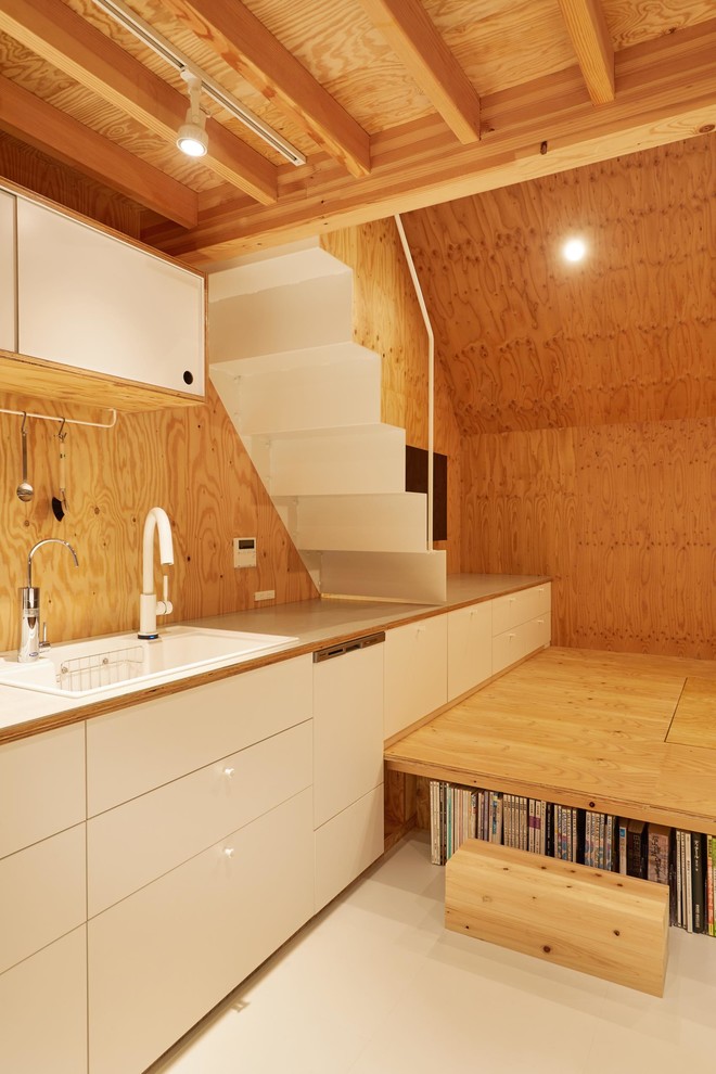 This is an example of a small arts and crafts single-wall open plan kitchen in Tokyo with white cabinets, white splashback, timber splashback, stainless steel appliances, no island, white floor and grey benchtop.