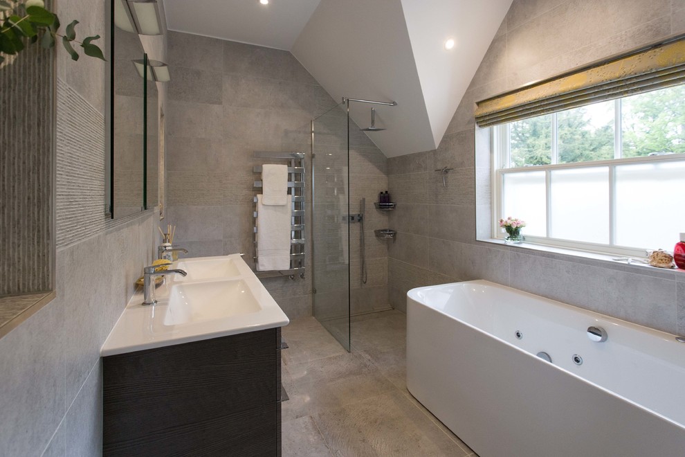 Large transitional master bathroom in Surrey with flat-panel cabinets, dark wood cabinets, a hot tub, an open shower, a wall-mount toilet, gray tile, ceramic tile, grey walls, ceramic floors, an integrated sink, grey floor and an open shower.