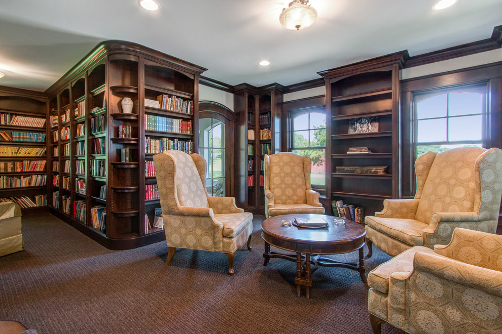 Inspiration for a mid-sized traditional home office in Milwaukee with a library, beige walls, carpet, no fireplace, a wood fireplace surround, a built-in desk and multi-coloured floor.