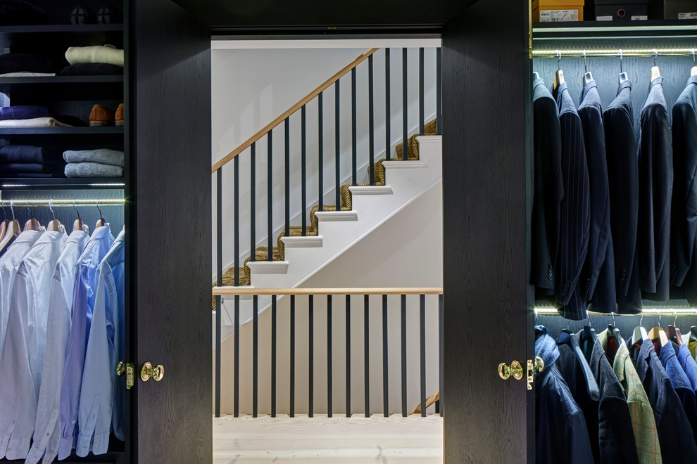 Photo of a mid-sized contemporary gender-neutral walk-in wardrobe in London with open cabinets, black cabinets and light hardwood floors.