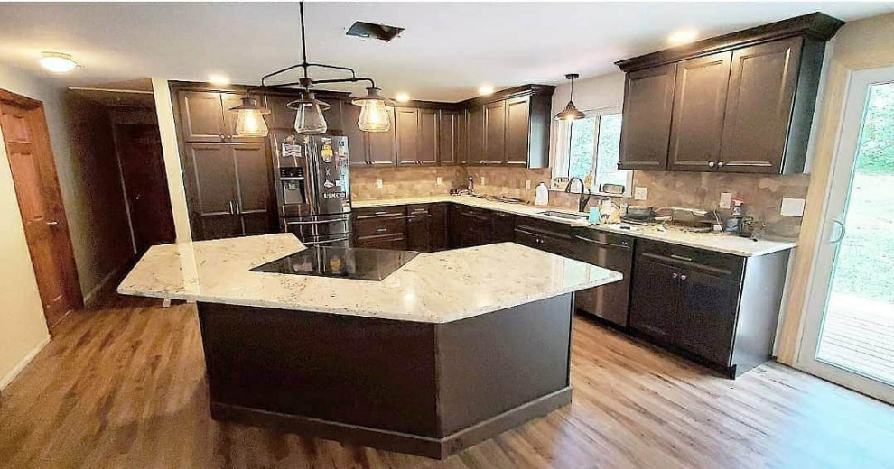 Mid-sized transitional l-shaped eat-in kitchen in Boston with an undermount sink, shaker cabinets, dark wood cabinets, granite benchtops, brown splashback, mosaic tile splashback, stainless steel appliances, laminate floors, with island, brown floor and beige benchtop.