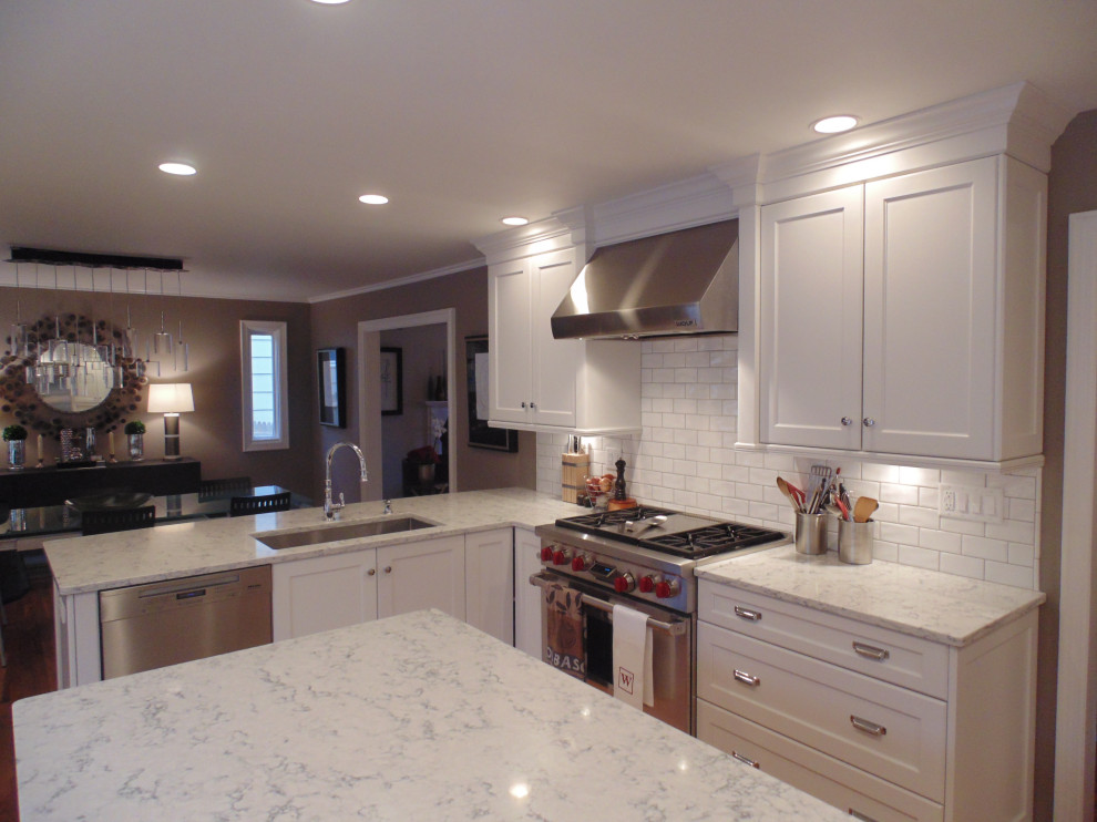 Inspiration for a large transitional u-shaped medium tone wood floor and brown floor eat-in kitchen remodel with an undermount sink, recessed-panel cabinets, white cabinets, quartz countertops, white backsplash, subway tile backsplash, stainless steel appliances, an island and white countertops