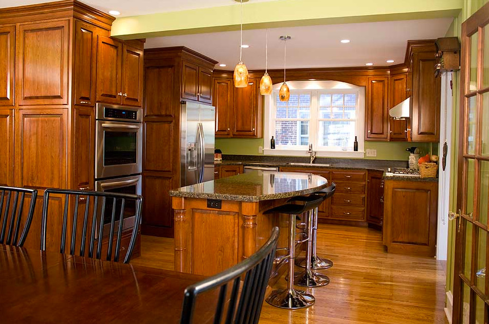 Inspiration for a mid-sized country u-shaped eat-in kitchen in Philadelphia with an undermount sink, raised-panel cabinets, medium wood cabinets, laminate benchtops, stainless steel appliances, medium hardwood floors and with island.