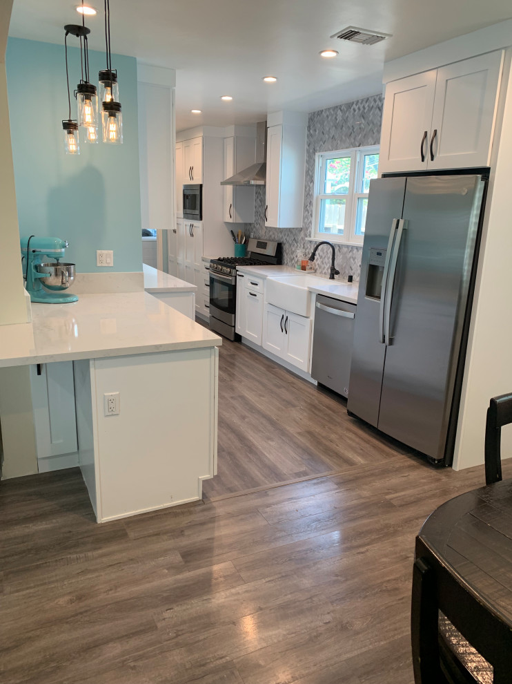 Mid-sized modern u-shaped eat-in kitchen in Los Angeles with an undermount sink, open cabinets, white cabinets, quartzite benchtops, multi-coloured splashback, glass tile splashback, stainless steel appliances, light hardwood floors, with island, brown floor, white benchtop and wallpaper.