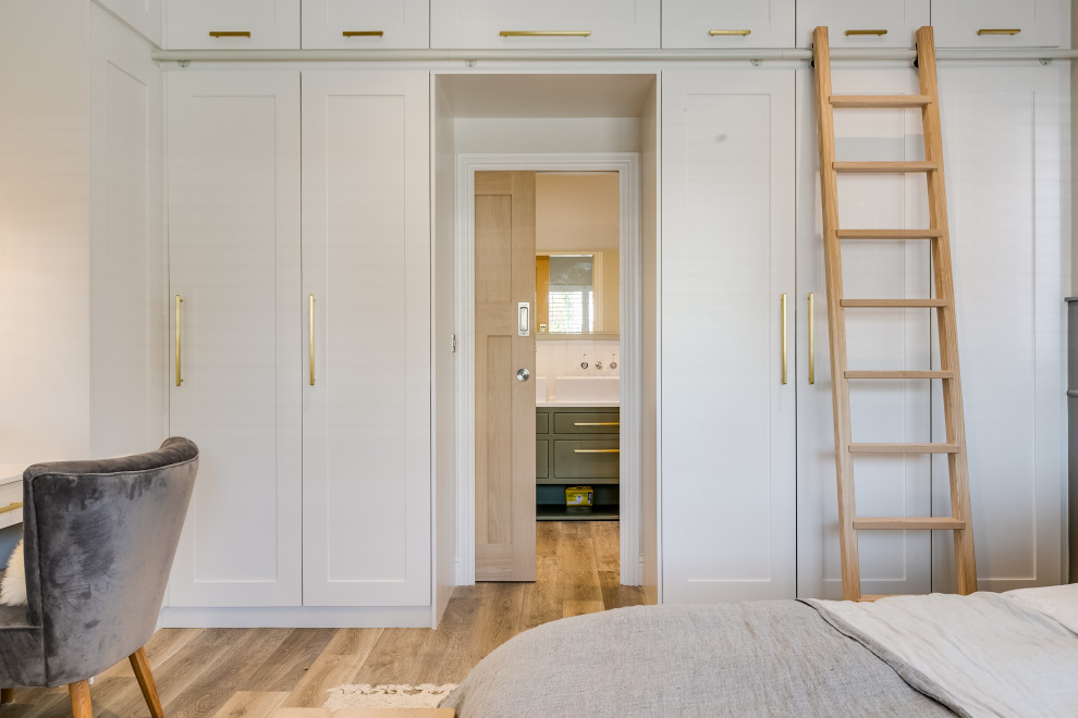 Стильный дизайн: хозяйская спальня среднего размера в стиле модернизм с серыми стенами, полом из ламината, коричневым полом и панелями на части стены без камина - последний тренд
