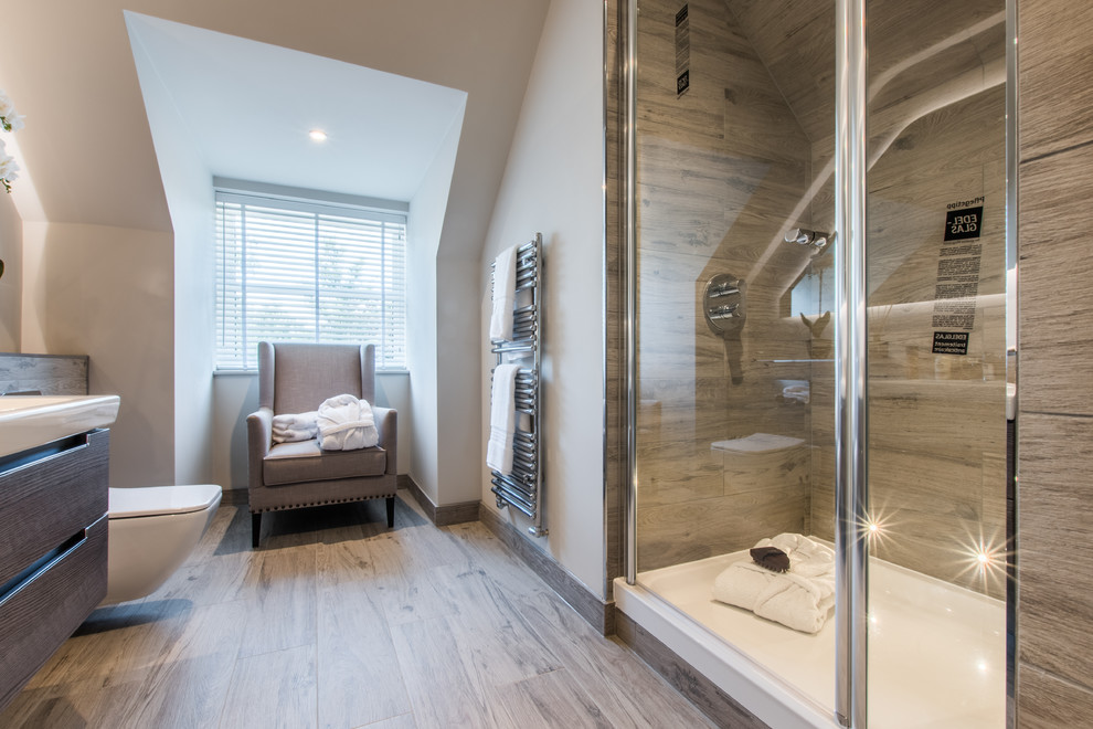 This is an example of a mid-sized contemporary bathroom in Berkshire with flat-panel cabinets, brown cabinets, a curbless shower, a wall-mount toilet, grey walls, a wall-mount sink, brown floor and a hinged shower door.