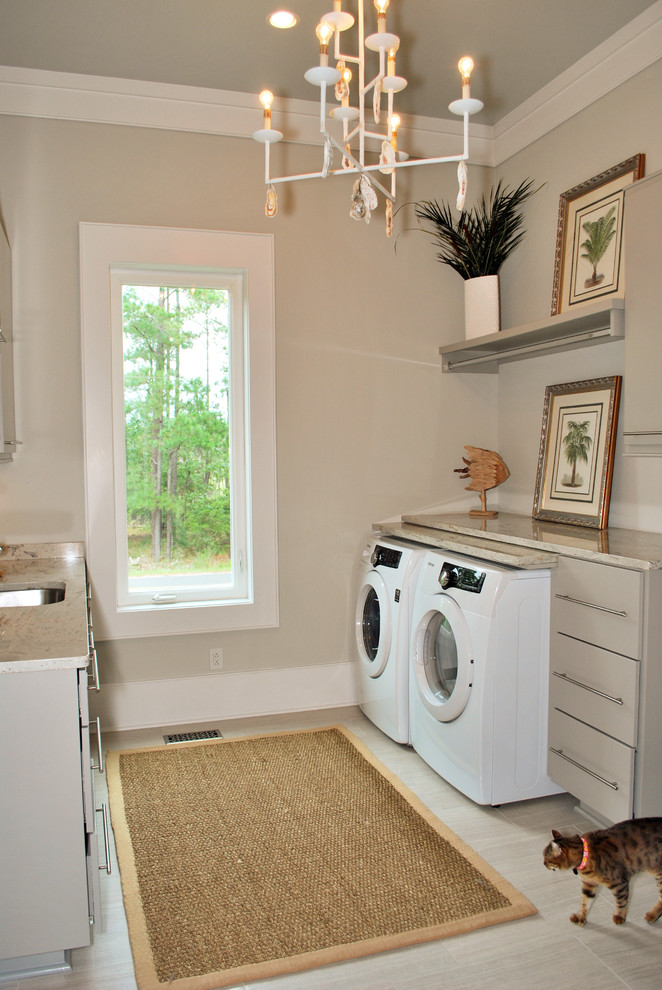 This is an example of a beach style laundry room in Charleston with grey floor, beige benchtop and grey cabinets.